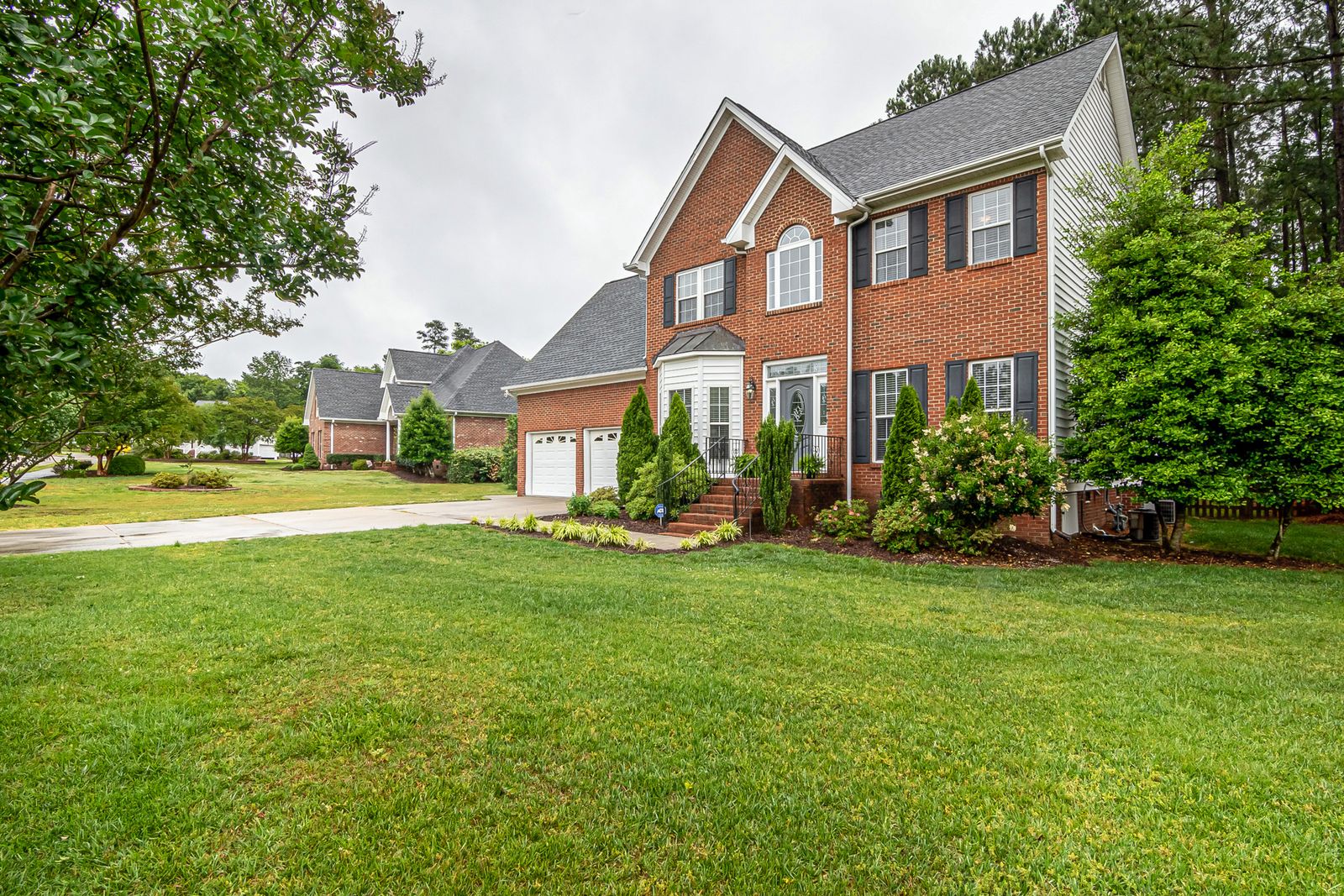 Brick two-story home with a front lawn; is now a good time to buy a house in the Triangle