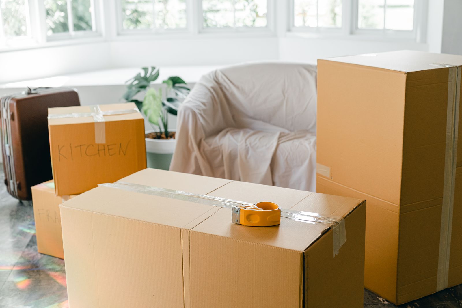 Moving boxes in an empty room while deciding to sell the house or rent it out